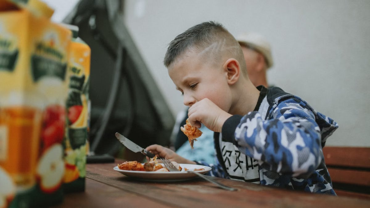 Young boy savoring a grilled chicken meal during an outdoor barbecue.